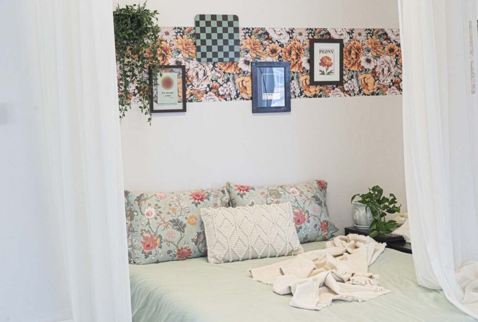 Landscape shot showcasing bedroom photography set. wallpaper and bedroom decor with framed art pieces. Floral notes.