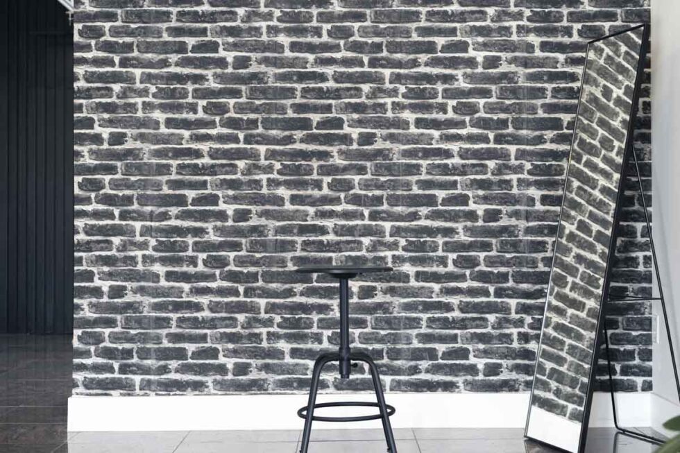 Landscape shot of minimalist industrial photography set. Black and white brick wallpaper with 1 stool and 1 full length floor mirror