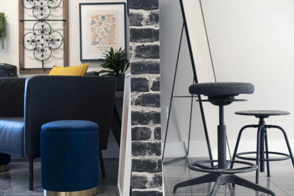 Landscape shot showcasing photography studio set variety with a maximalist set on left and minimalist set on right divided by black brick wall.