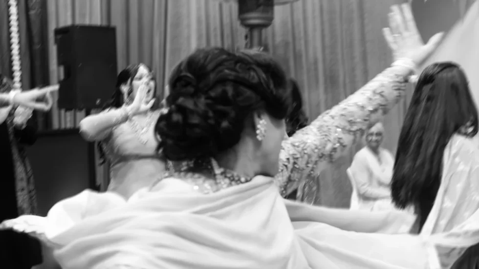 Women performing giddha at an Indian celebration, arms raised in synchronized motion