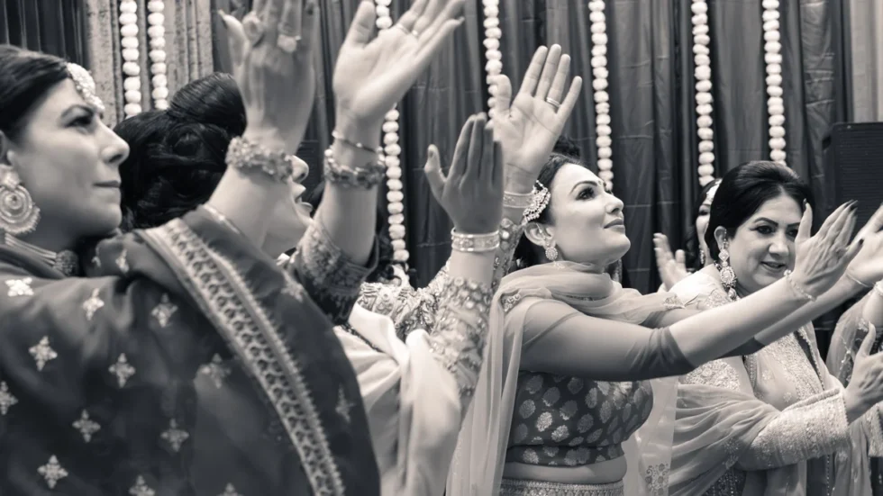 Women dancing with raised hands at an Indian wedding celebration