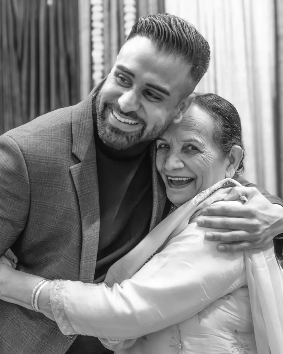 Grandson and grandmother sharing a warm embrace at a wedding event, captured by Origin Story Studio