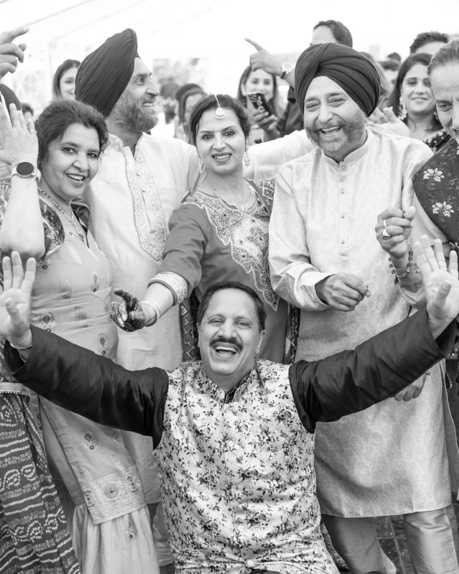 Group of guests dancing and celebrating in traditional attire during a wedding event, captured by Origin Story Studio